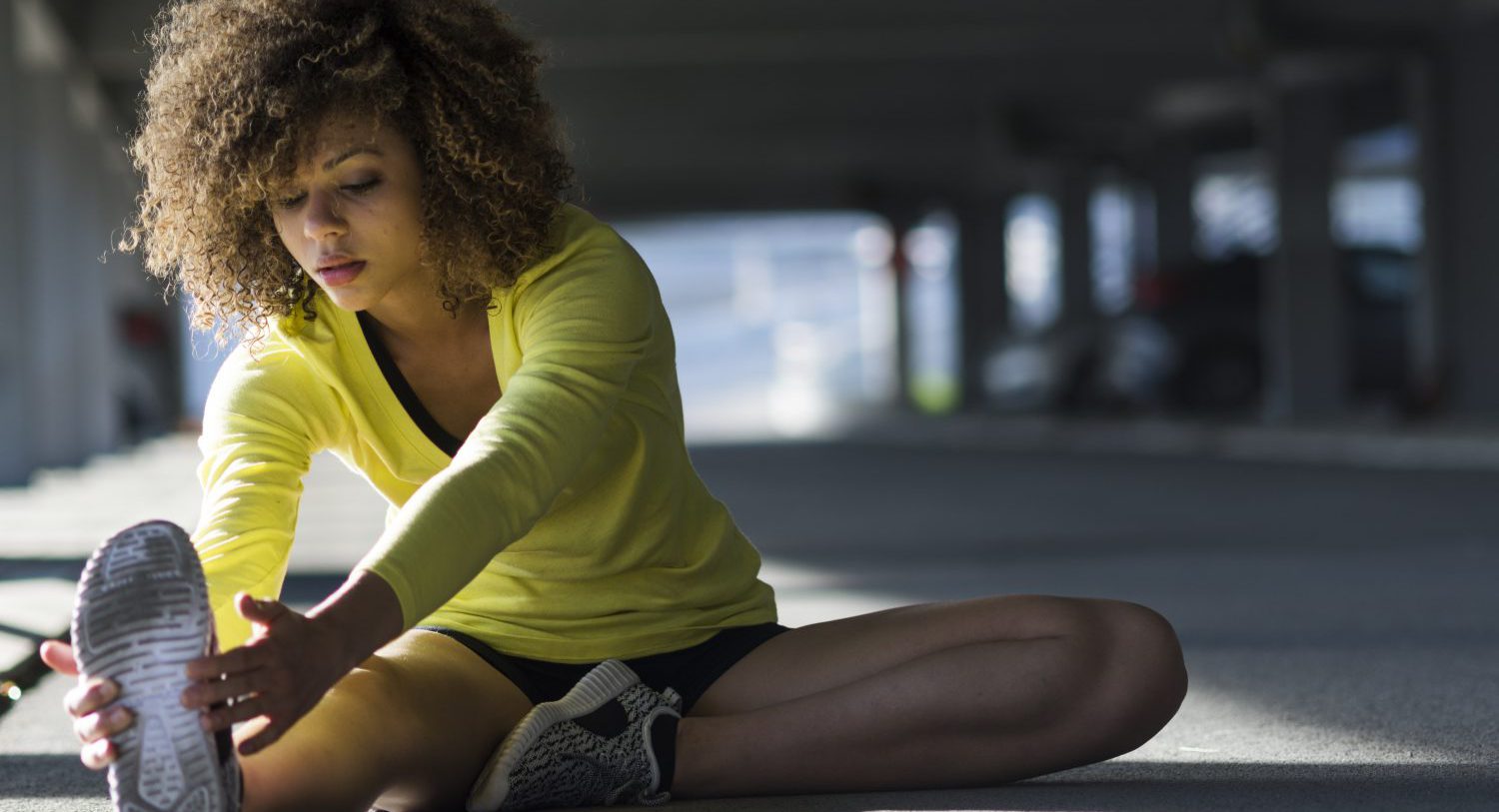Woman stretching and listening to the music on her headphones