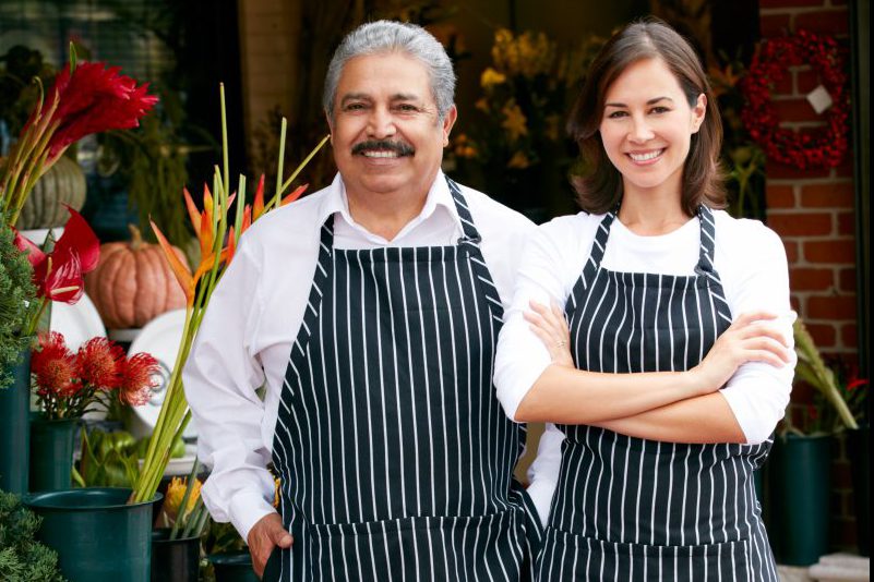 Male and female florist smiling outside shop