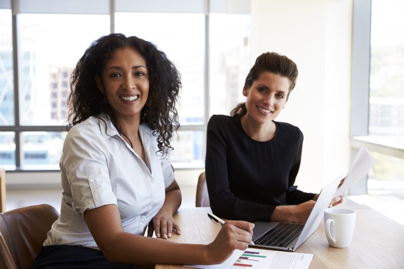 Portrait Of Two Businesswomen With Laptop Computer In Office